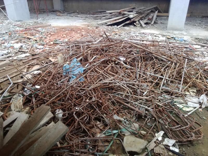 Tas de ferrailles de chantier mêlées à des planches de bois, des plastiques et des gravats