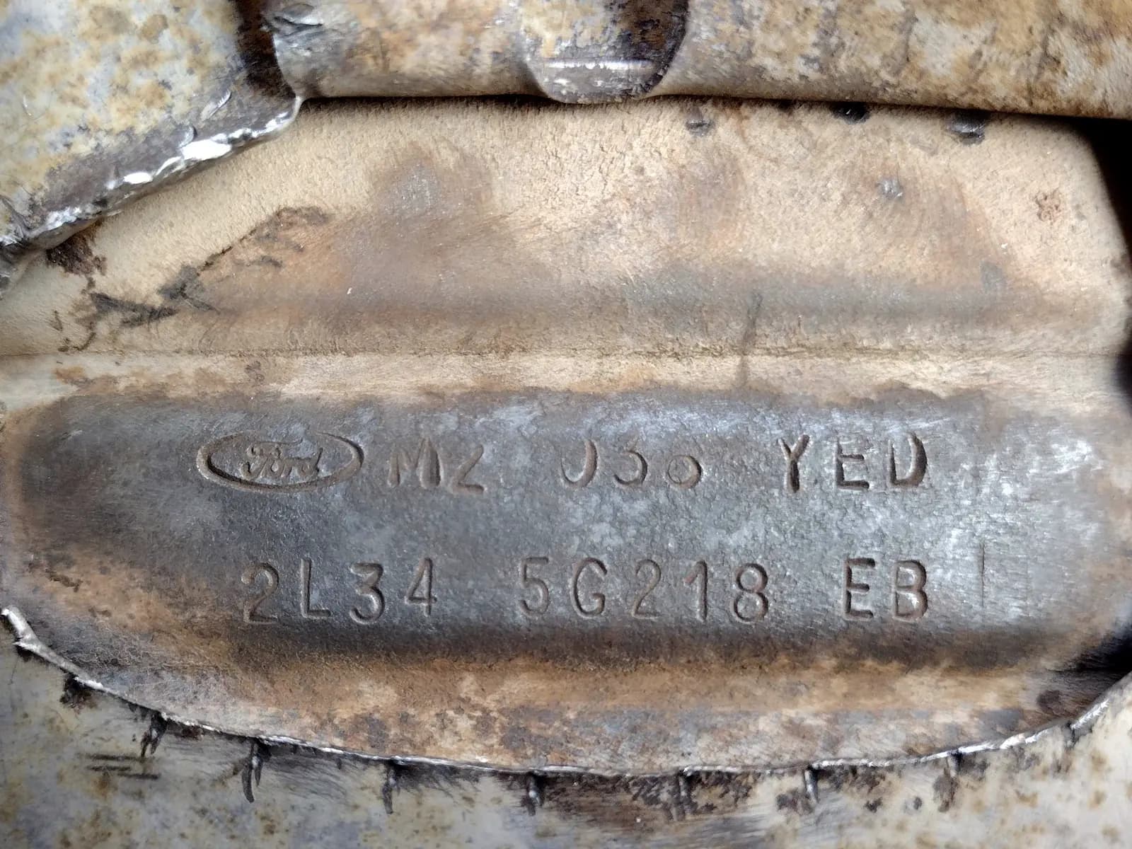 Référence constructeur estampée sur la coque d’un catalyseur automobile : logo, code alphanumérique et numéro de pièce